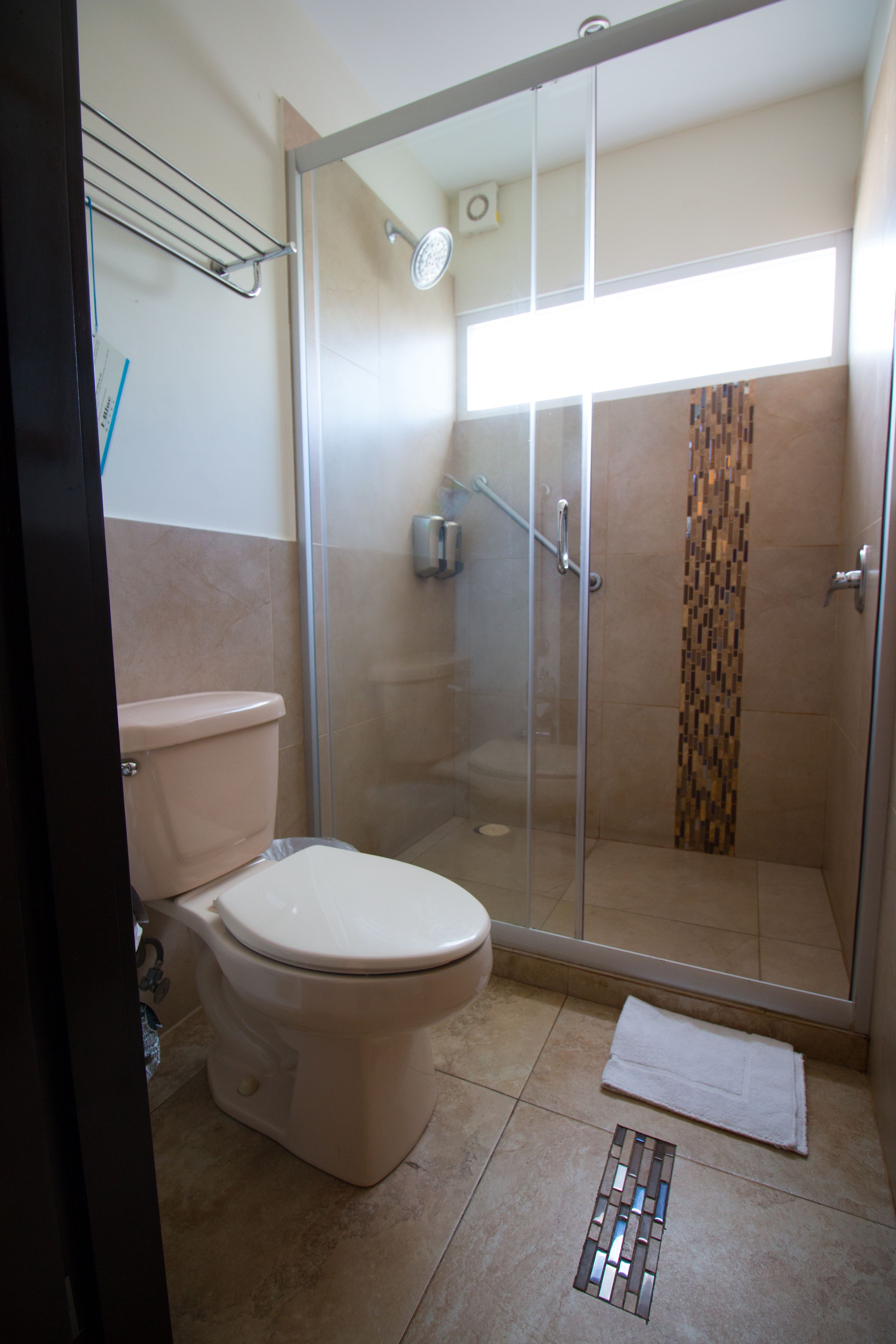 Un bagno con doccia vetro, servizi igienici e pavimento piastrellato.
