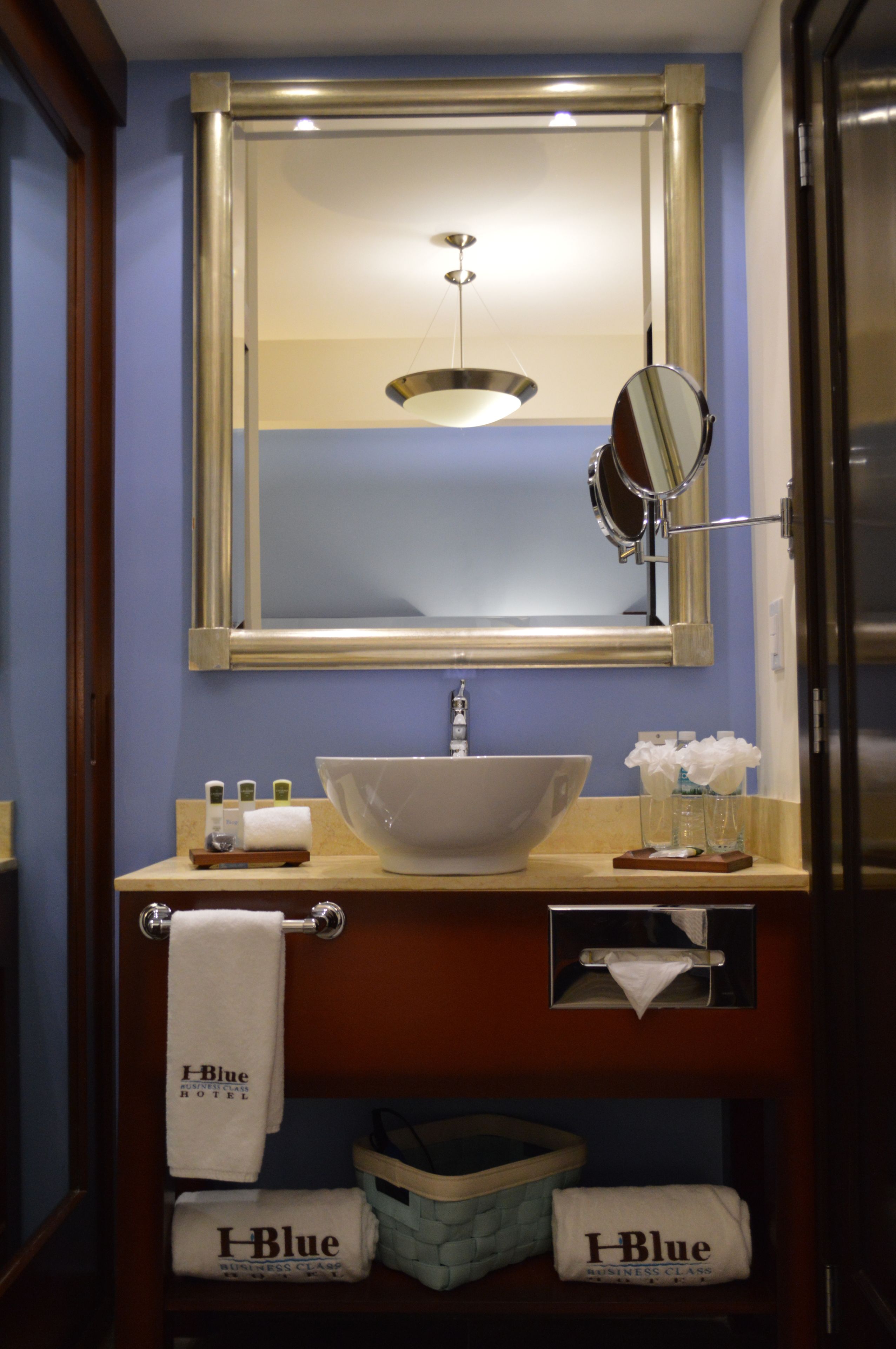 A bathroom with a white sink, a mirror, and a towel rack with towels.