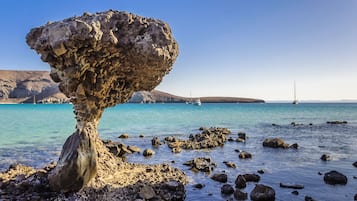 Una costa rocosa con aguas azules cristalinas y una formación rocosa destacada.