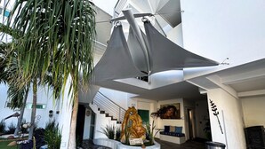 A modern building with a curved pathway, a palm tree, and a statue. - Hotel HBlue Centro (La Paz)