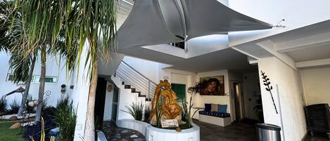 Un bâtiment moderne avec un chemin sinueux, un palmier et une statue.