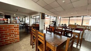 A restaurant with brick walls, wooden tables and chairs, and large windows. - Pumamarca Guest House (Cusco)
