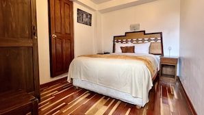 A bedroom with a wooden bed, a nightstand, a wooden wardrobe, and a framed picture on the wall. - Pumamarca Guest House (Cusco)