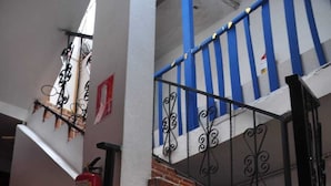A staircase with red brick steps, black metal railings, and a fire extinguisher on the wall. - Pumamarca Guest House (Cusco)
