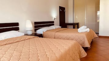 Una habitación de hotel con dos camas, una mesita de noche, una lámpara y un armario.