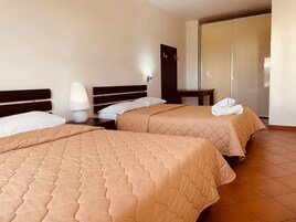 Una habitación de hotel con dos camas, una mesita de noche, una lámpara y un armario.