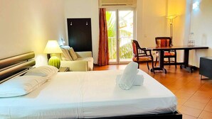 A hotel room with a bed, a desk, a chair, a lamp, and a view of the outdoors. - RDG Hotel (Managua)