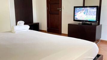 Ein Hotelzimmer mit Bett, Fernseher, Kleiderschrank und Spiegel.