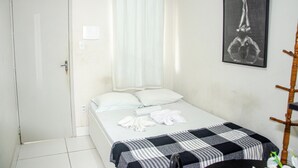 A neatly made bed with a checkered blanket, a white pillow, and rolled towels. - Studio 51 (Jaboatão dos Guararapes)
