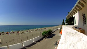 A beach with umbrellas and lounge chairs, a clear sky, and a building with a balcony. - Hotel Villaggio Club ALTALIA (Brancaleone)