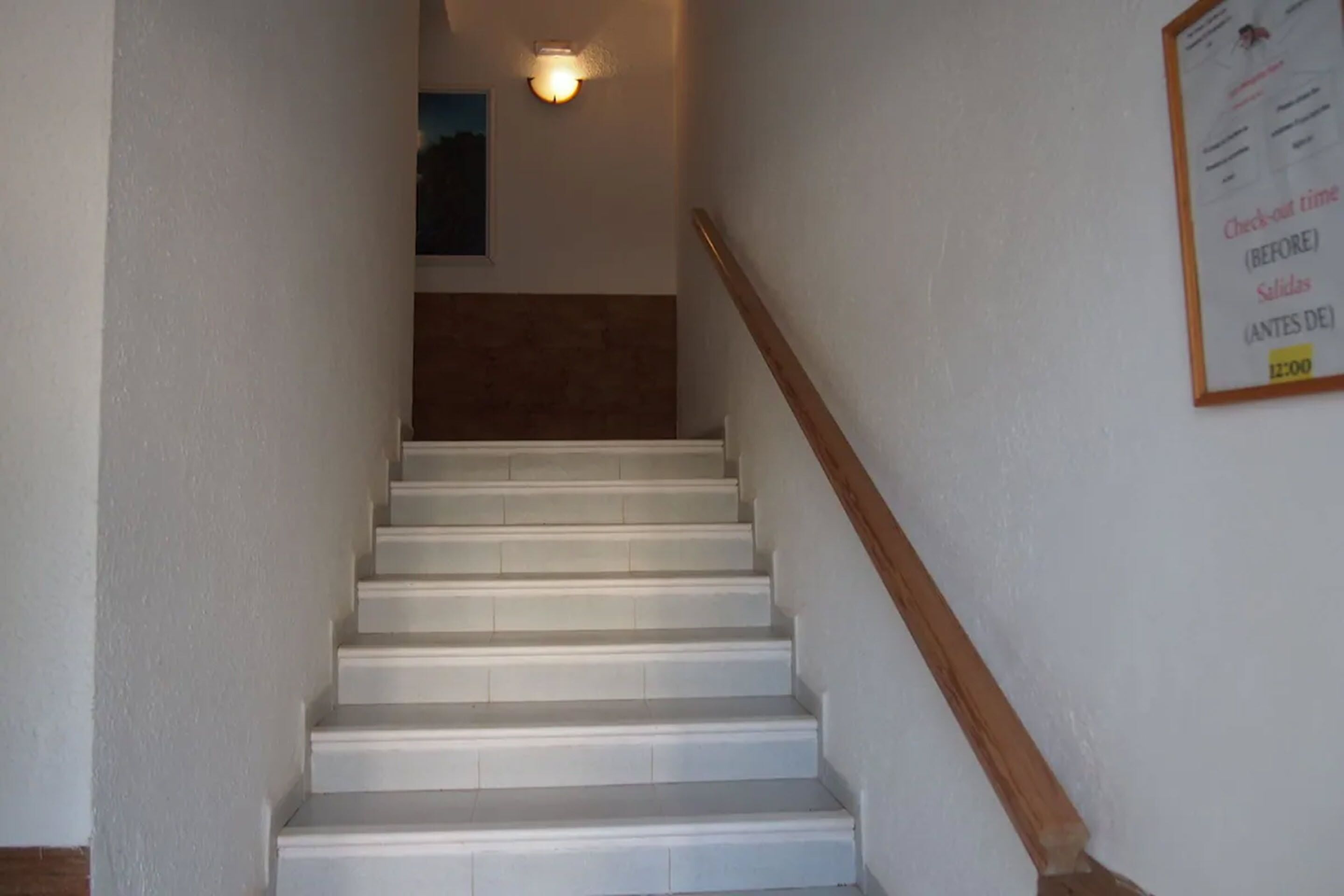 Eine Treppe mit weißen Stufen und einem Holzgeländer.