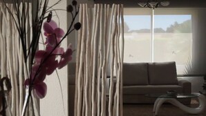 Ein modernes Wohnzimmer mit einer Couch, einem Glastisch und einer dekorativen Pflanzengestaltung.
