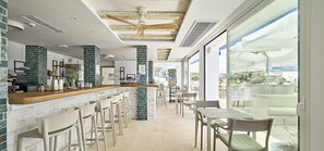 A modern bar area with a counter, stools, and a view of the outdoors. - Hostal Lago Playa II (Formentera)