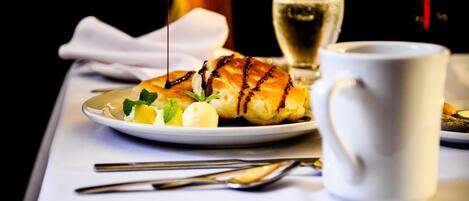 A dessert plate with a pastry, a glass of white wine, and a white mug on a table.