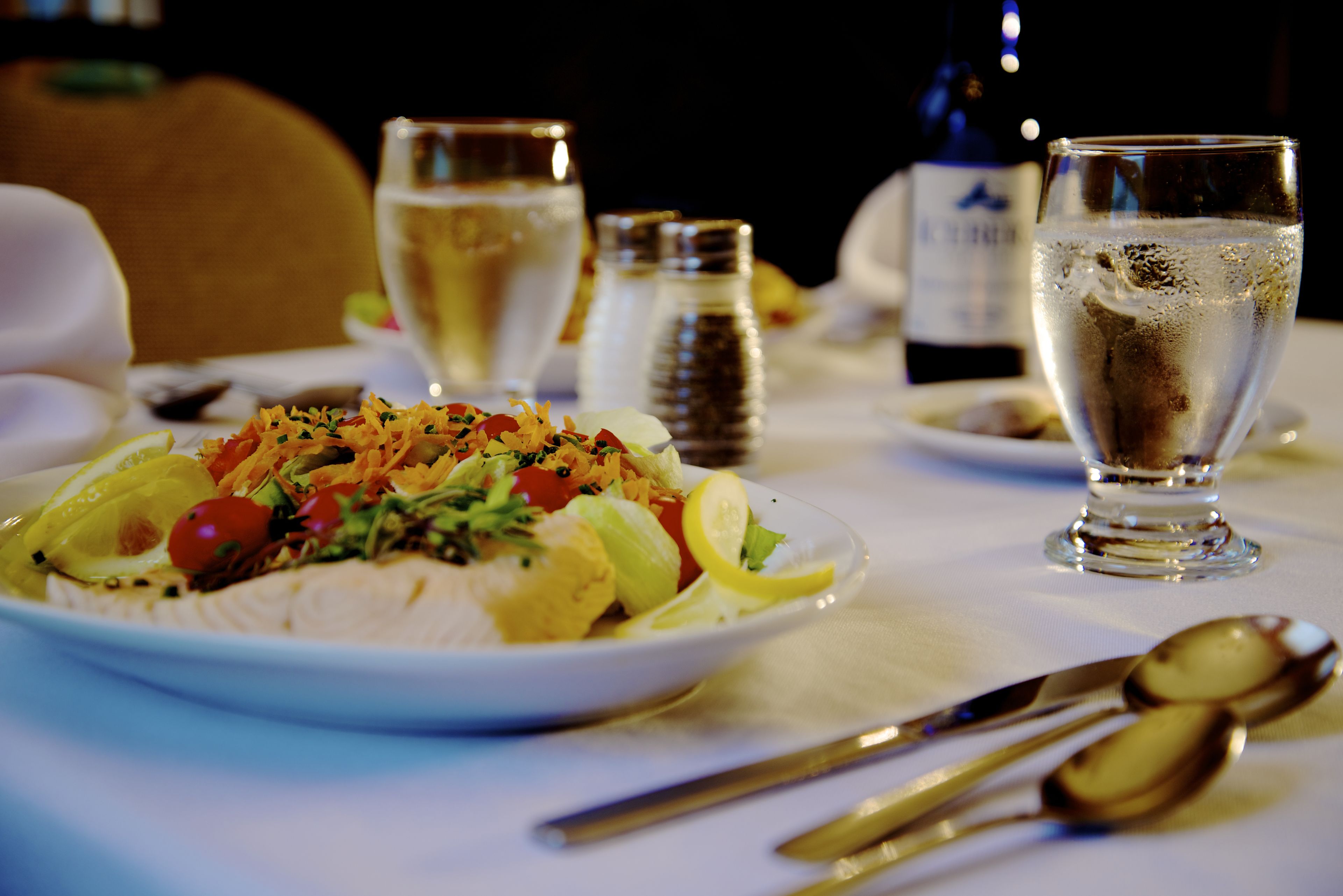 A dining table with a plate of food, glasses, and cutlery.