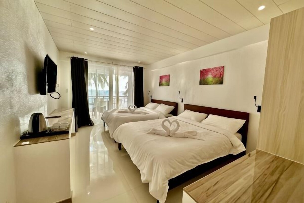 Une chambre d’hôtel avec deux lits, une télévision, un bureau et une vue sur l’extérieur.