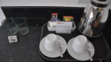 Una bandeja con dos tazas y platillos blancos, una cafetera y una tarjeta de menú sobre una encimera negra.
