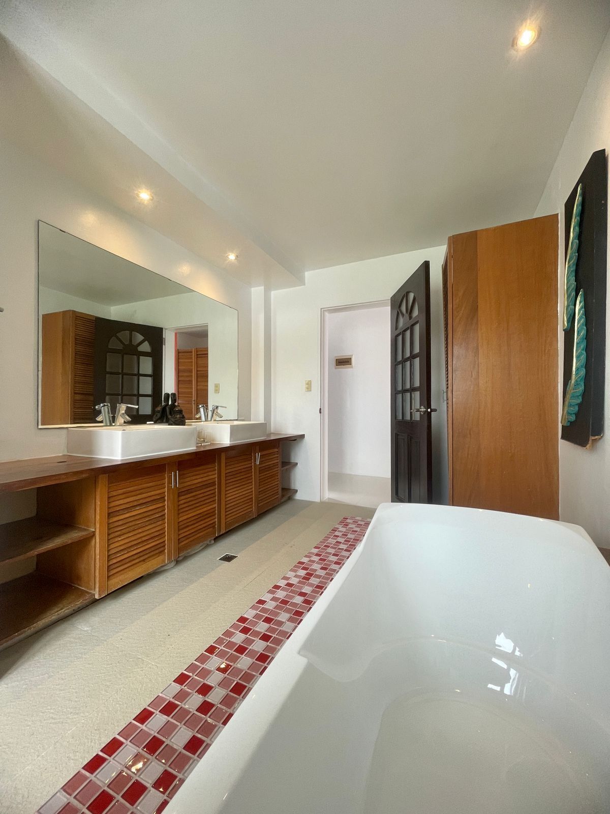 Une salle de bain moderne avec un grand miroir, un meuble-lavabo en bois et une baignoire blanche.