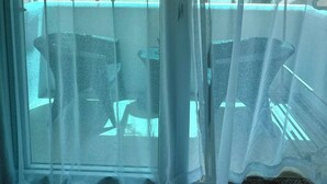 A room with a view of a beach and palm trees through sheer curtains. - Calypso Beach & Dive Resort (Boracay Island)