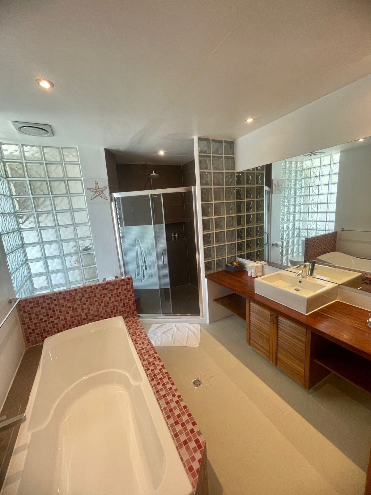 Ein modernes Badezimmer mit Badewanne, Duschbereich und Waschtisch mit großem Spiegel.