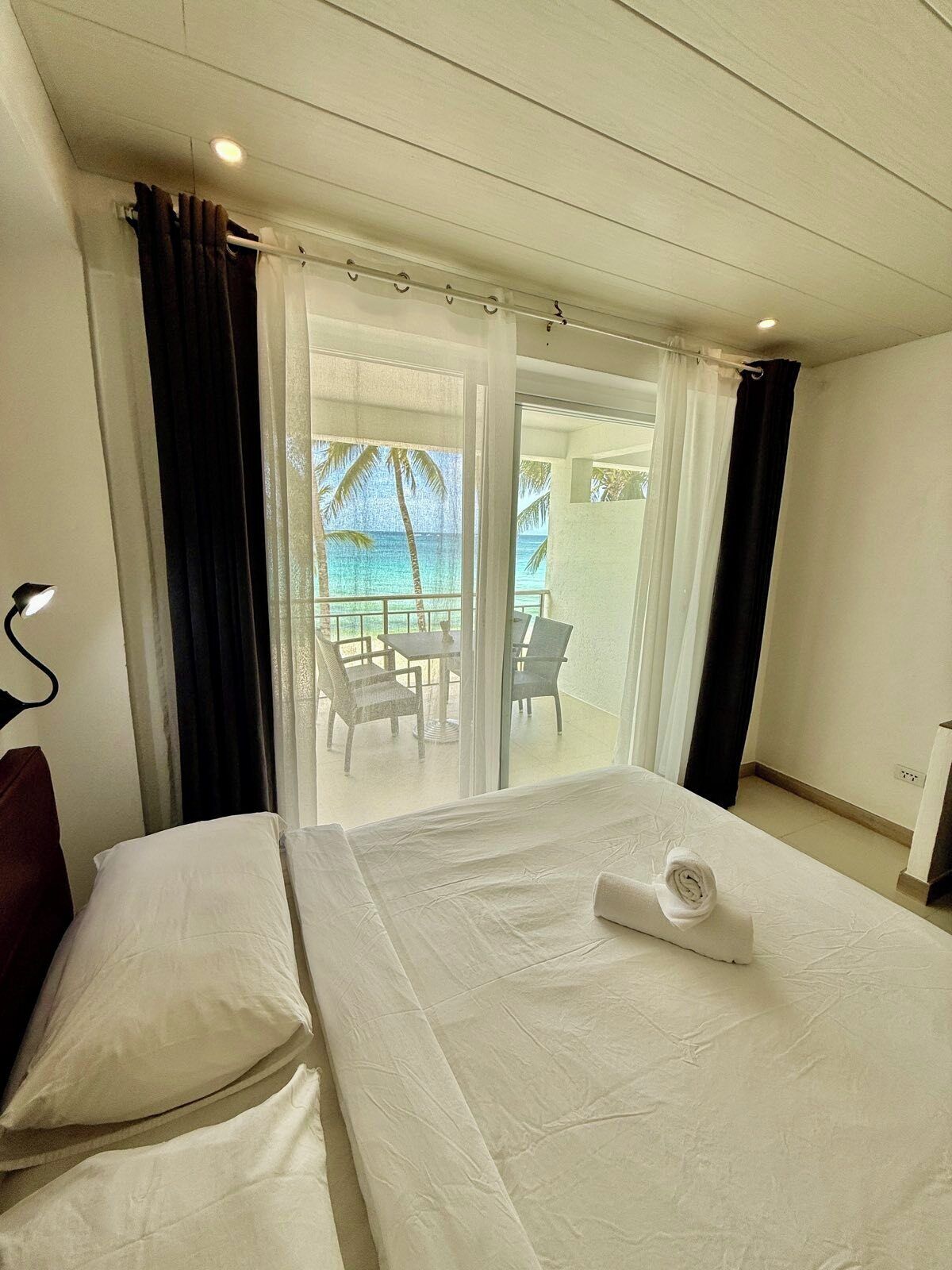 A hotel room with a bed, a desk, and a view of the ocean.