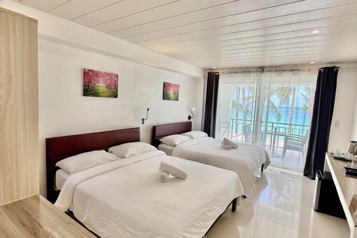 Habitación de hotel con dos camas, un balcón con vistas y obras de arte en las paredes.