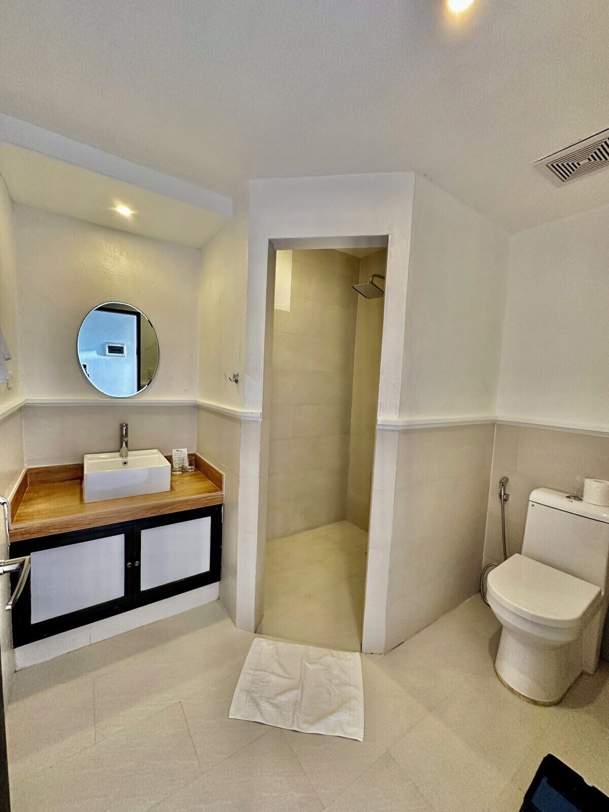 A modern bathroom with a sink, mirror, toilet, and shower.