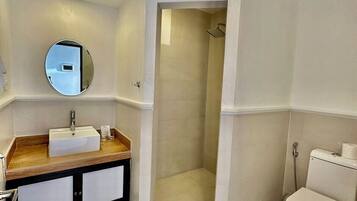 A modern bathroom with a sink, mirror, toilet, and shower.