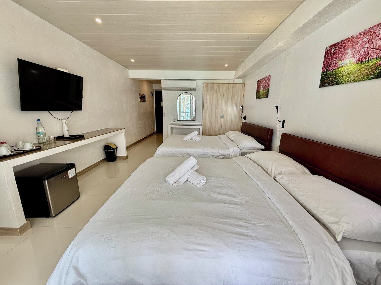 Een hotelkamer met twee bedden, een televisie, een klein bureau en een raam.