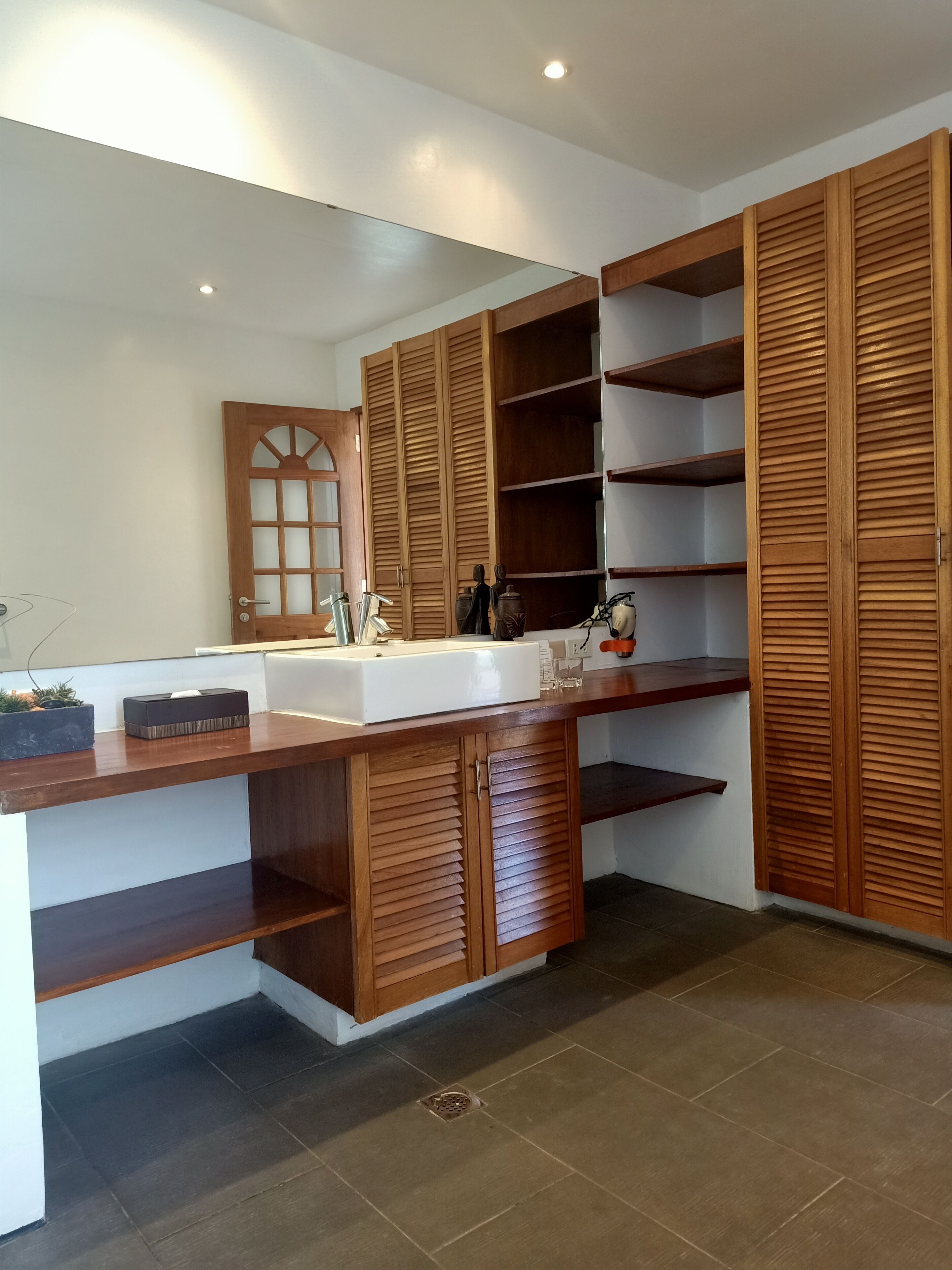 A modern bathroom with a large mirror, wooden cabinets, and a vanity with a sink.