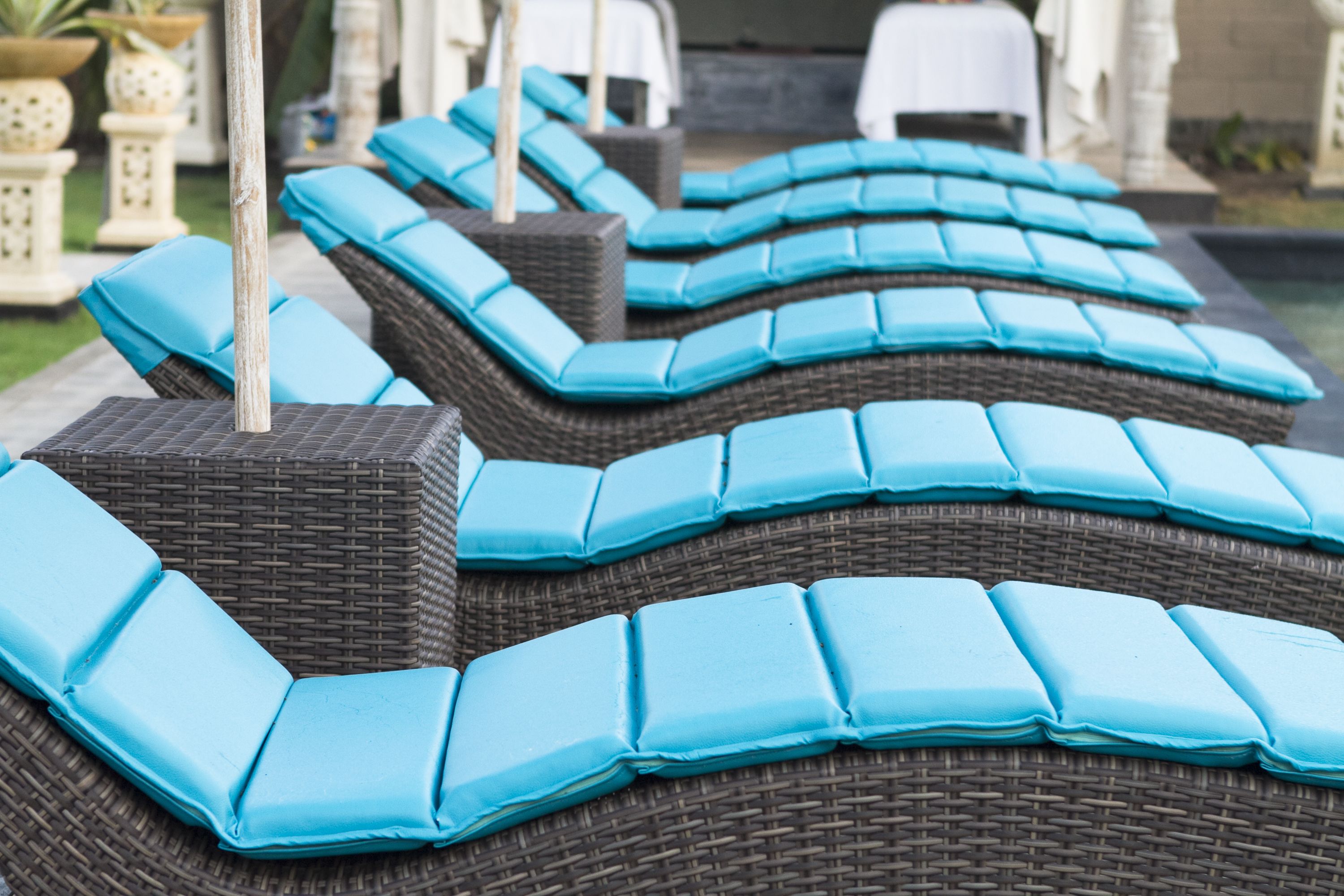 A row of wicker lounge chairs with blue cushions.