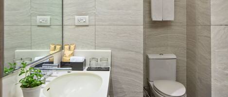 Un baño moderno con lavamanos, espejo, artículos de aseo y retrete.