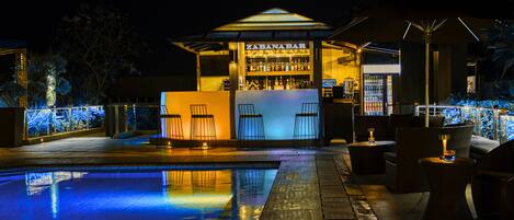 An outdoor bar area with a pool, bar stools, and a bar counter.