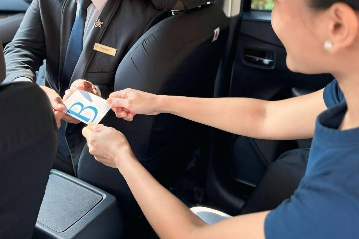 A person handing over a card to another person in a car.