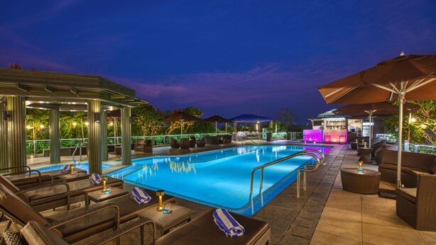 A poolside area with lounge chairs, a bar, and umbrellas.