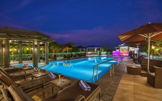 Una piscina al aire libre, sombrillas, sillones reclinables de piscina