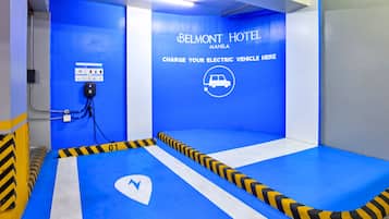 A blue parking area with a sign for Belmont Hotel Manila, charging station, and directional arrows.