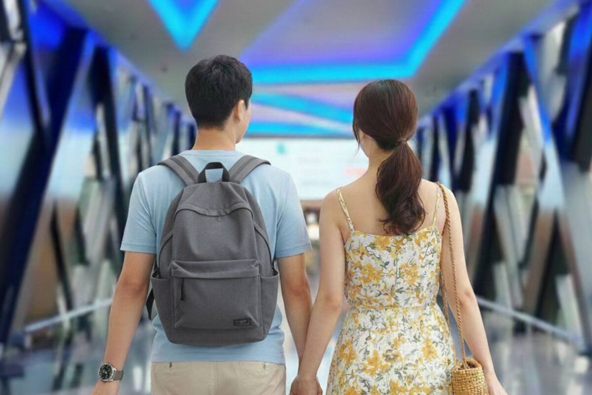 A couple walking through a corridor with a modern design, featuring blue lighting and a glass ceiling.