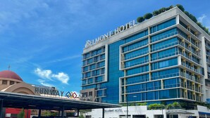 A modern hotel with a prominent "BELMONT HOTEL" sign, multiple floors, and a covered walkway.