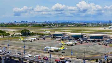 Un aéroport où plusieurs avions sont stationnés, une tour de contrôle et, au loin, une vue sur la ville.