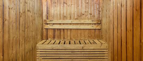 Una sauna in legno con panche e un catino di legno.