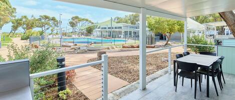 A covered patio with a pool view, outdoor seating, and a view of the pool area.