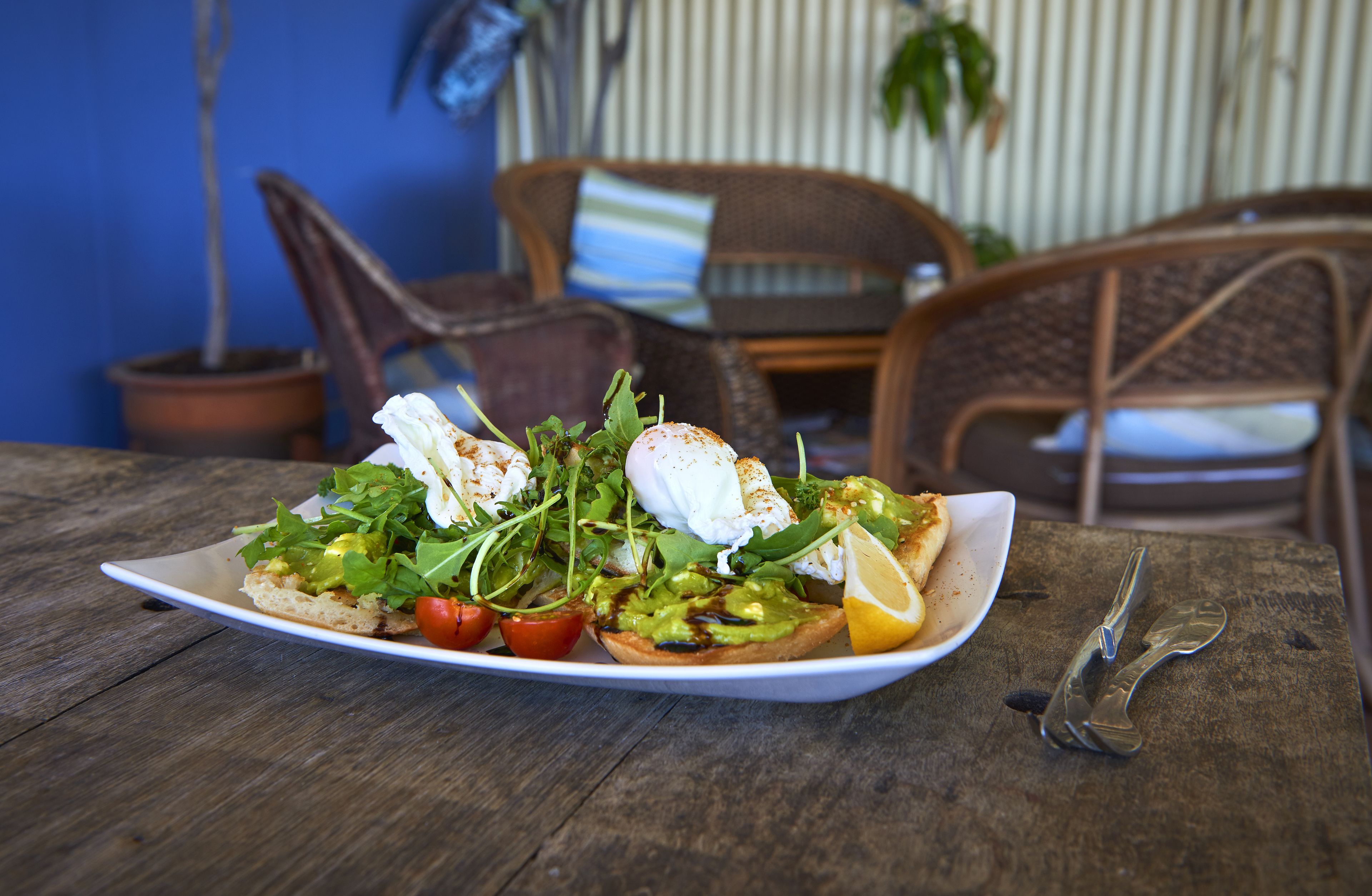 A plate of food on a wooden table with a chair and a plant in the background.