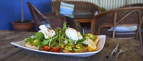 A plate of food on a wooden table with a chair and a plant in the background.