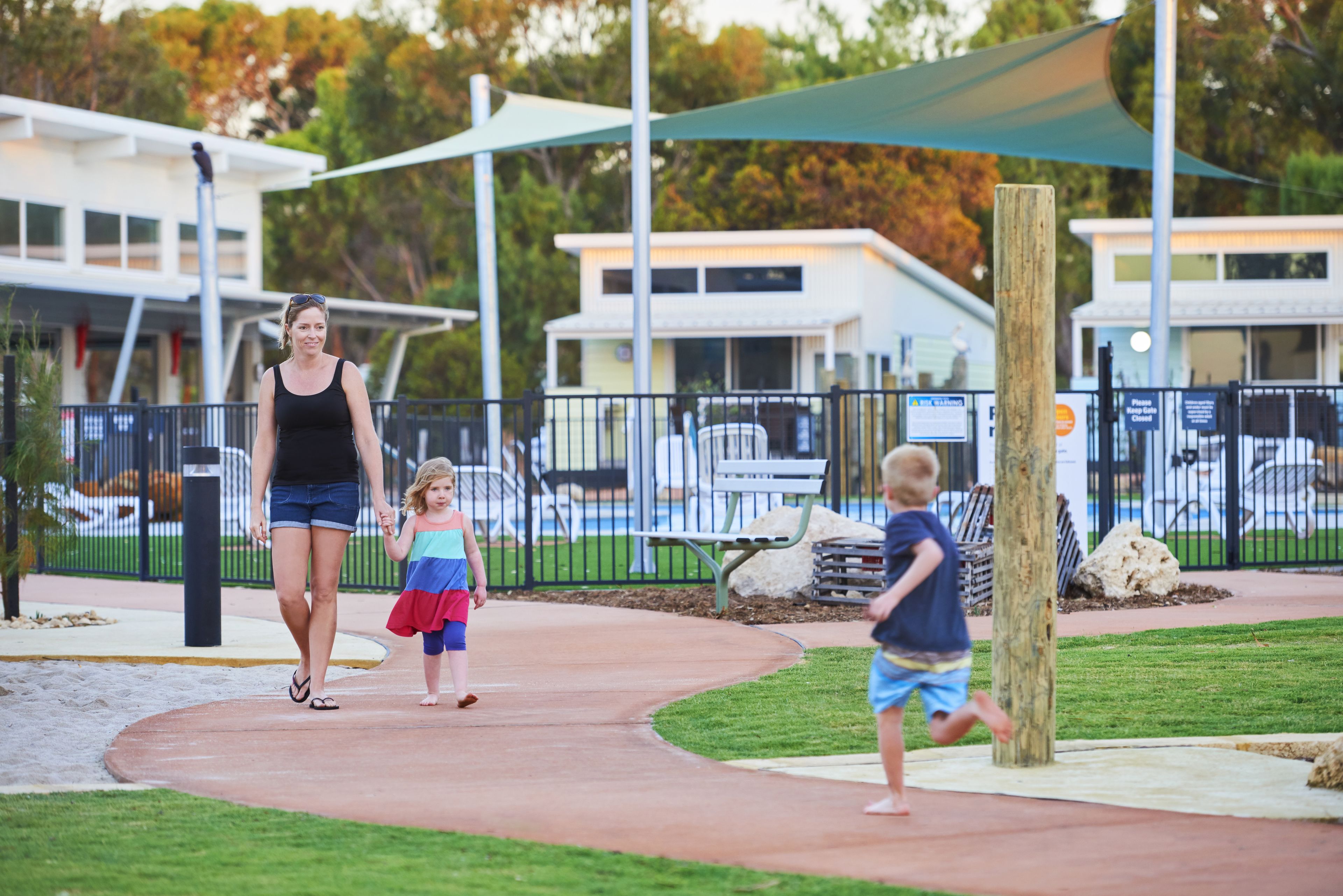 A pathway in a park with a woman and two children walking.