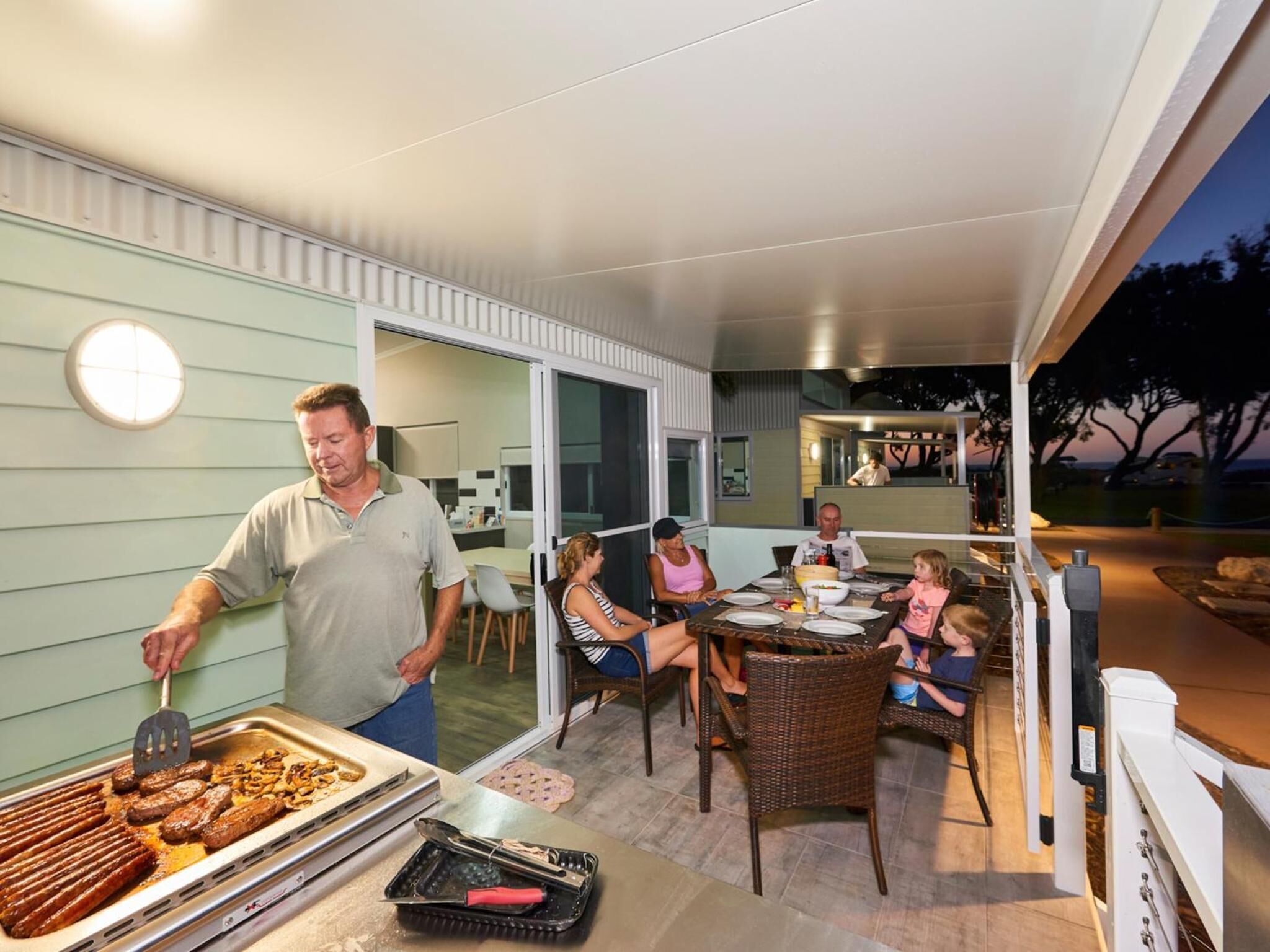 An outdoor dining area with a grill station, dining tables, and chairs.