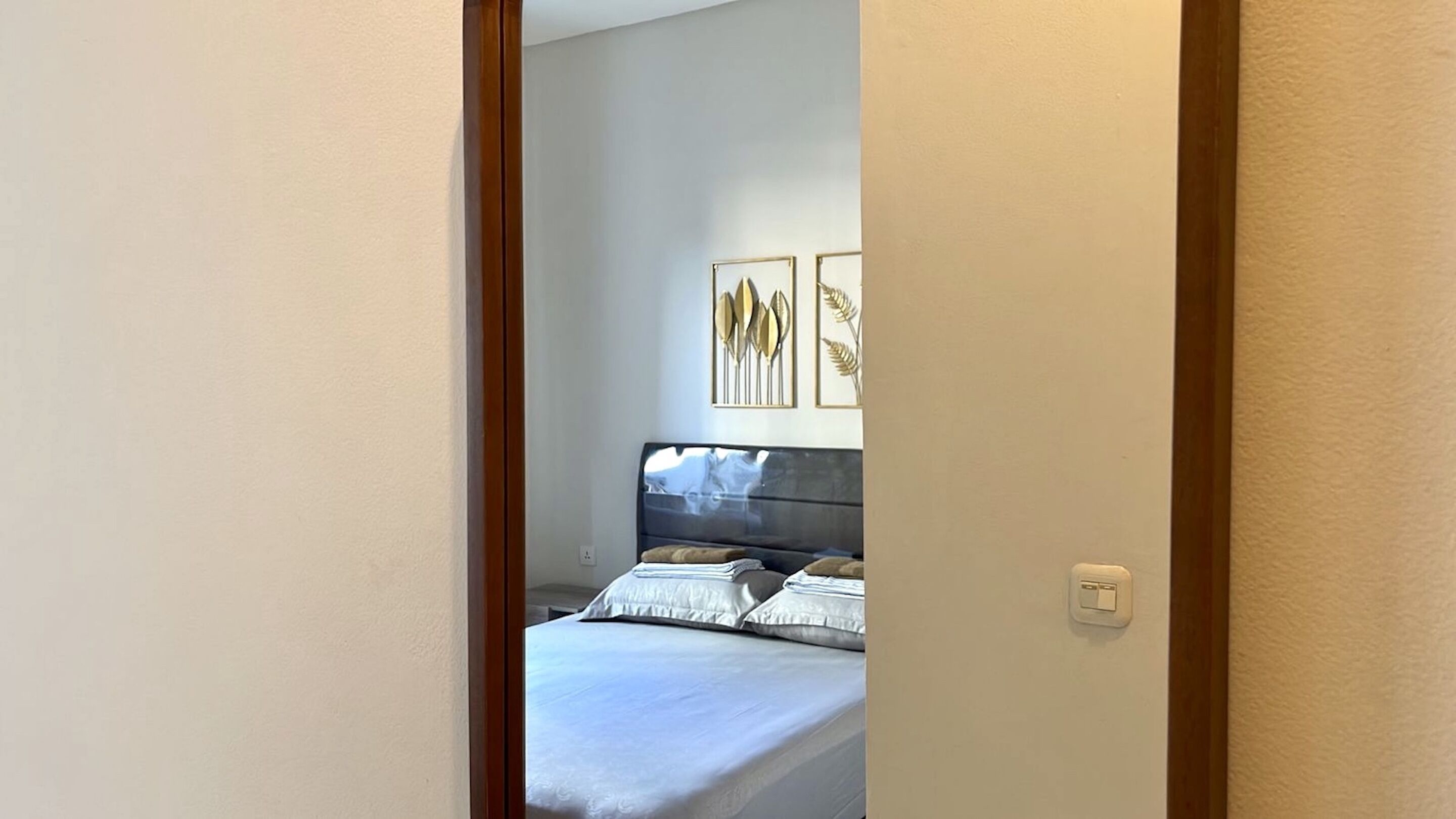 Quarto com cama, almofadas e duas obras de arte emolduradas na parede.