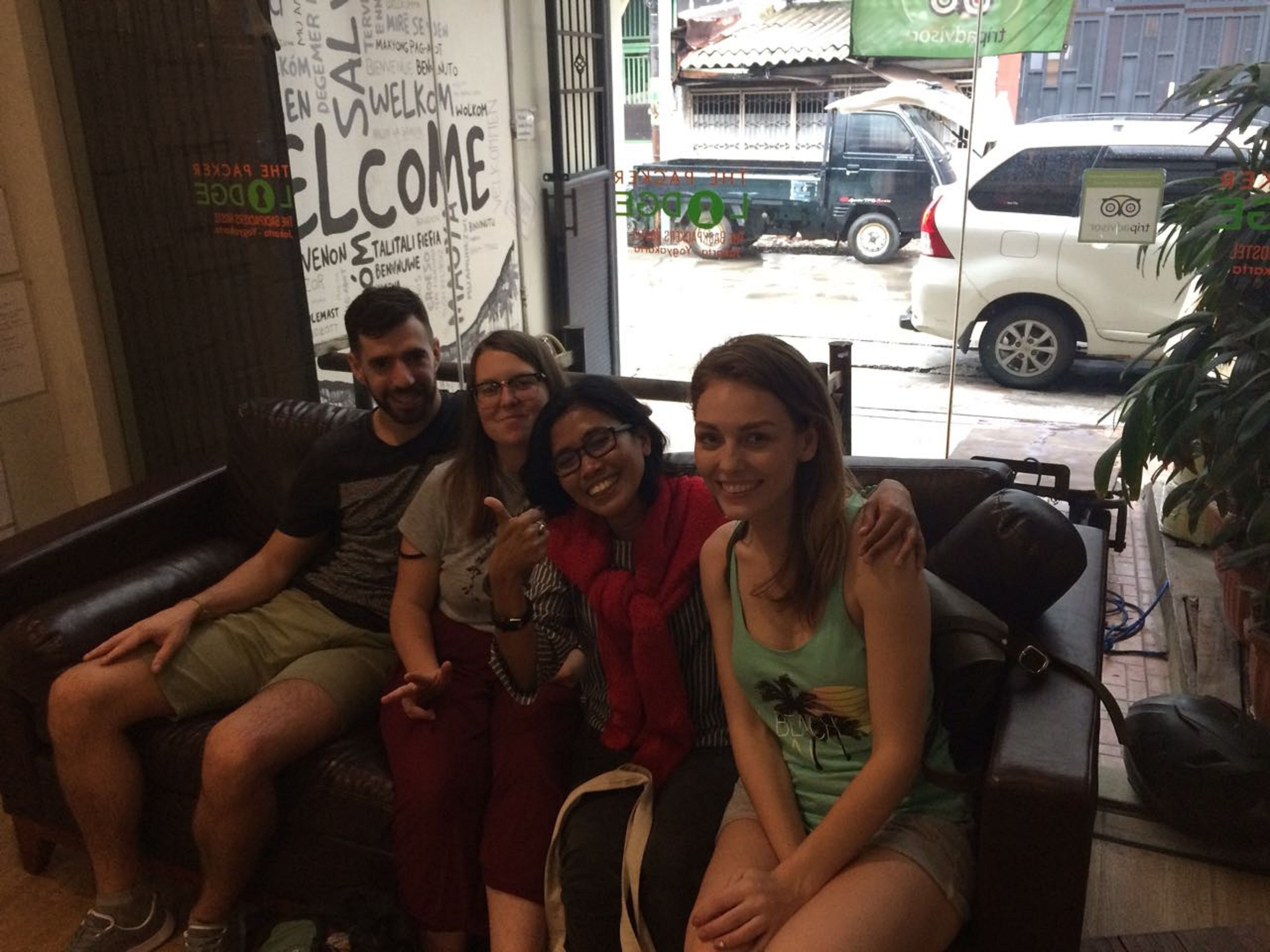 A group of people sitting on a leather couch in a room with a large window displaying a cityscape.
