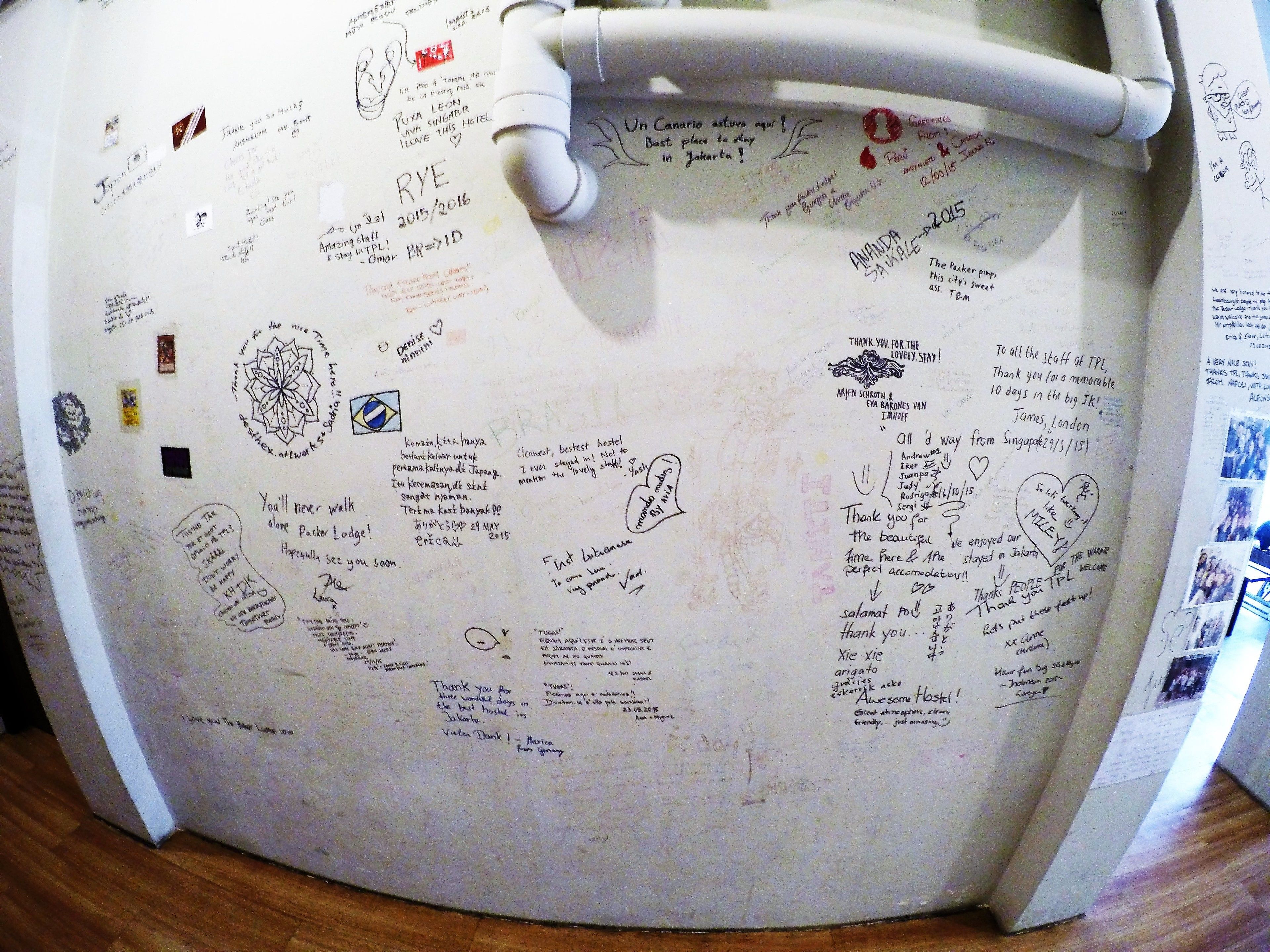 A wall covered with handwritten notes and drawings, likely from guests, with various messages and doodles.