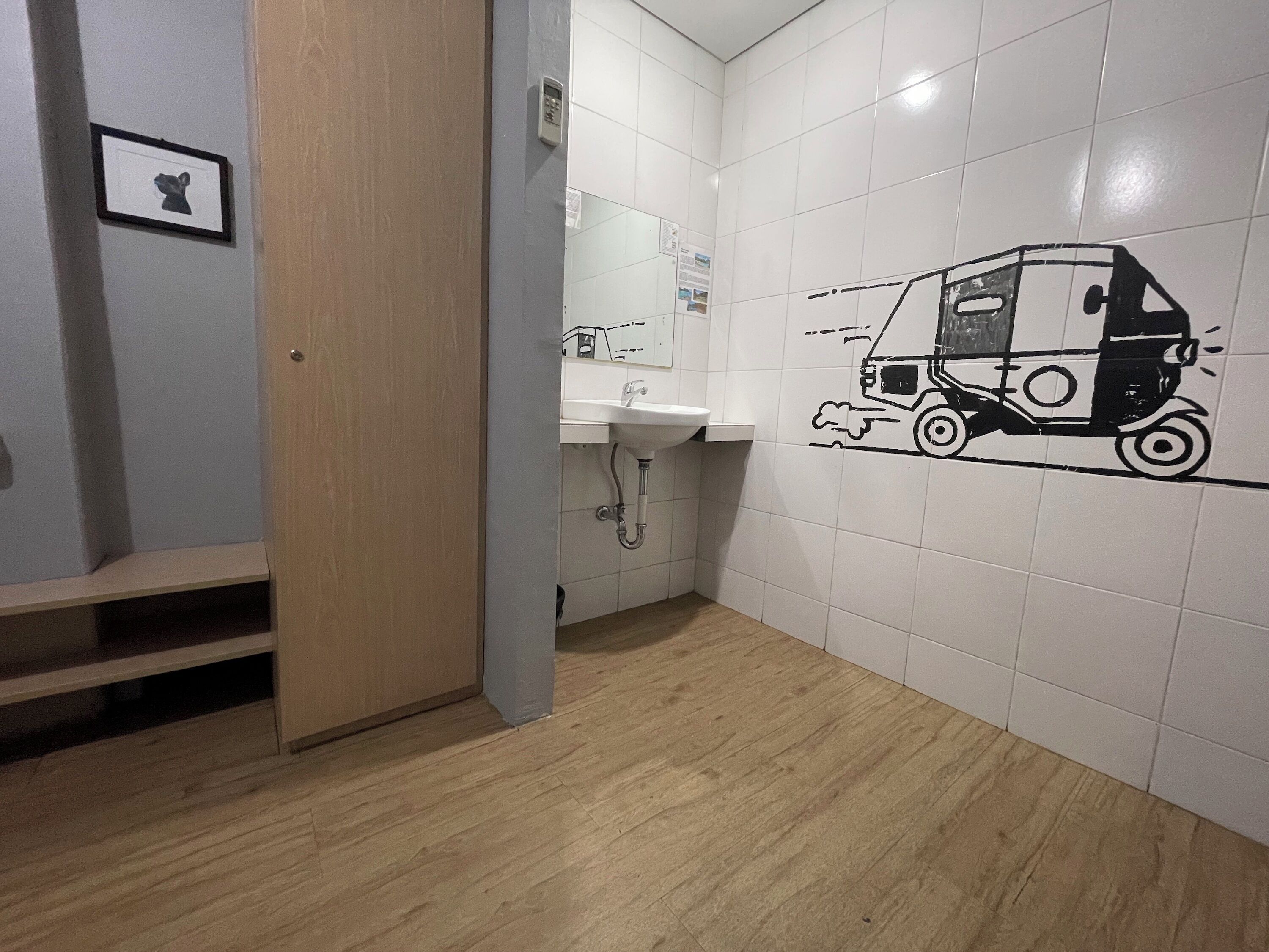 A restroom with a sink, a toilet, and a wall with a black and white drawing of a delivery truck.